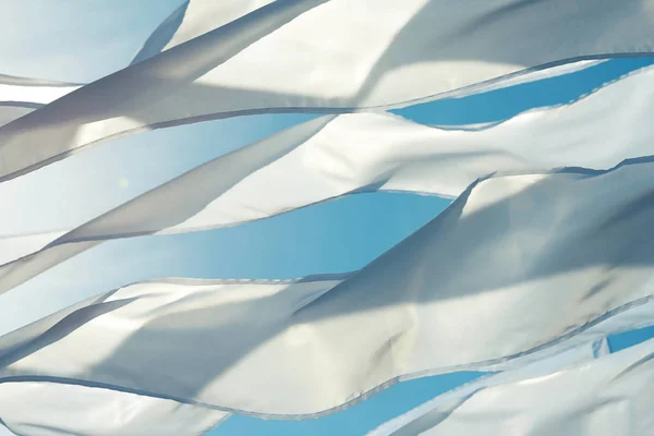 Bir sallayarak beyaz uzun triungular bayrakları ve bir arka plan parlak blu gökyüzü şeritler