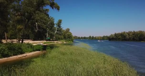 Flug über die Küste mit Schilf und Strand mit Urlaubern an Bord. — Stockvideo