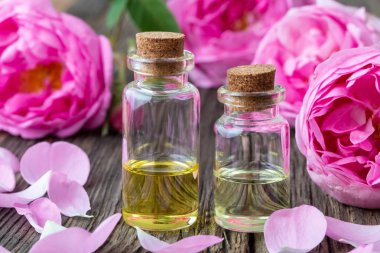 Uçucu yağ ile taze gül koyu ahşap arka plan üzerinde iki şişe
