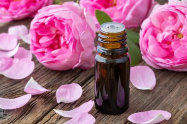 Esans ile taze gül ahşap arka plan üzerinde koyu bir şişe