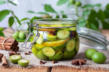 Macerating olgunlaşmamış ceviz, limon ve ev yapımı tentür hazırlamak için bir kavanoza alkol içinde baharatlar