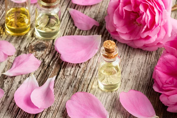 Esans ile taze gül ahşap bir masa üzerinde bir şişe