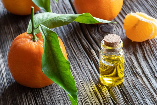Taze mandalinalı bir şişe turunçgil yağı.