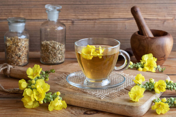 A cup of herbal tea with fresh mullein flowers on a rustic background