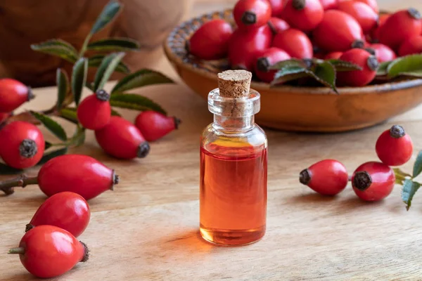 A bottle of rosehip seed oil with fresh fruit