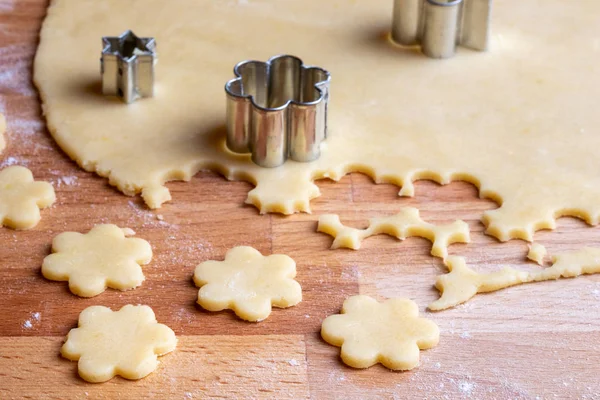 Cutting out flower shapes from rolled out dough to prepare traditional Linzer Christmas cookies