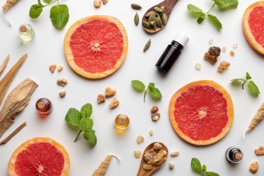 Taze greyfurt, nane şekeri, beyaz sandal ağacı, kardamon ve diğer malzemelerle birlikte gerekli yağ şişeleri.