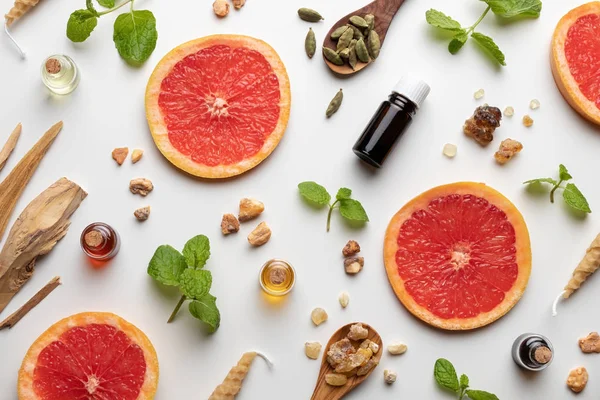 Taze greyfurt, nane şekeri, beyaz sandal ağacı, kardamon ve diğer malzemelerle birlikte gerekli yağ şişeleri.