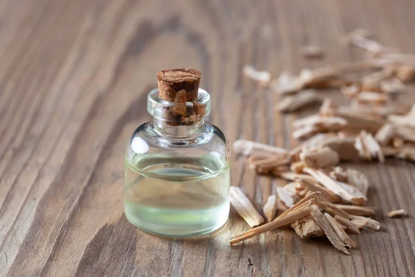 Una botella de aceite esencial de cedro con trozos de madera de cedro — Foto de Stock