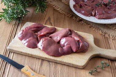 Fresh raw chicken livers on a cutting board clipart