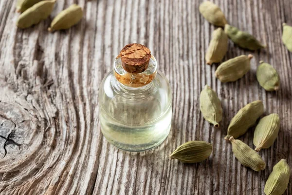 Una botella de aceite esencial de cardamon con semillas de cardamon —  Fotos de Stock