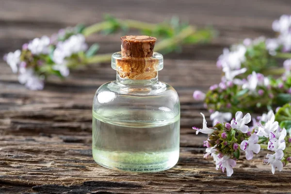 Een fles van essentiële tijmolie met takjes verse tijm — Stockfoto