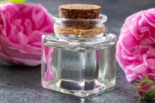 Бутылка розового эфирного масла с цветами роз — стоковое фото