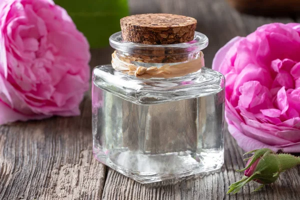 Бутылка розового эфирного масла с цветами розы де май — стоковое фото