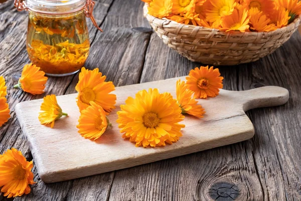 Calendula blomster på et skærebræt med tinktur - Stock-foto