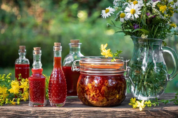 Bottles of red oil made from St. John\'s wort flowers, outdoors