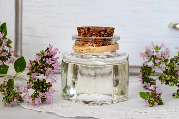 Бутылка эфирного масла с цветущими ветками орегано — стоковое фото