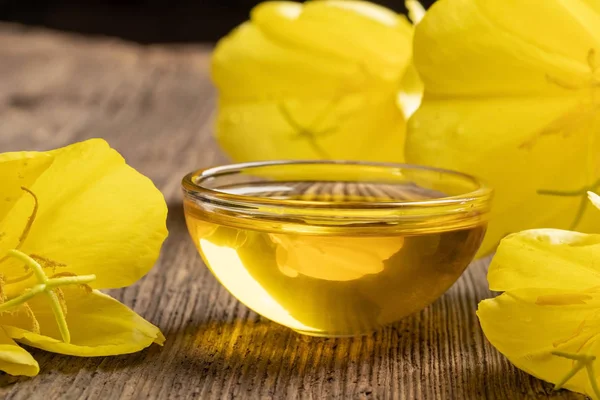 Un tazón de aceite de onagra con flores de onagra — Foto de Stock