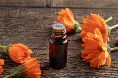 Turuncu çiçekli koyu renkli bir yağ şişesi.