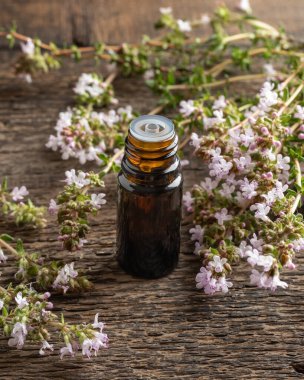 Çiçek açan kekik bitkisi ile birlikte bir şişe gerekli yağ.
