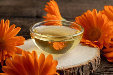 Masasında taze takviye çiçekleri olan küçük bir kase gerekli yağ.