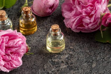 A bottle of essential oil with roses on a dark background clipart