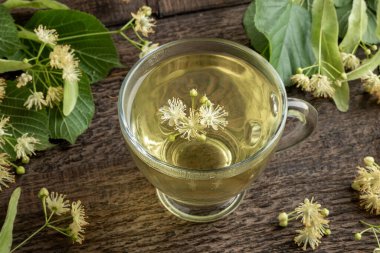 Masada ıhlamur çiçekleri olan bir fincan bitki çayı.