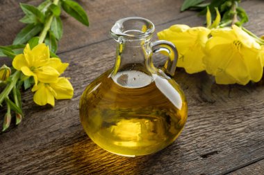 Bir şişe çuha çiçeği yağı ve masada taze çiçek.