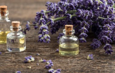 Ahşap bir arka planda taze açan lavanta içeren bir şişe gerekli yağ.
