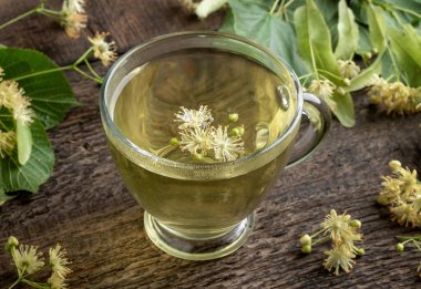 Masadaki şeffaf fincanda ıhlamur çiçeği çayı.