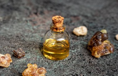 Gri arka planda tütsü reçinesi olan bir şişe temel yağ.