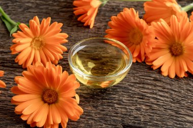 Çiçek açan takvim bitkisi ile birlikte bir kase gerekli yağ.