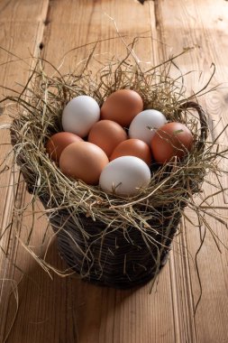 Tahta bir masada hasır bir sepette çiğ yumurta.