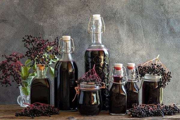 Bottles of black elder syrup with fresh elderberries and leaves