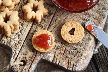 Ev yapımı daire şeklindeki Linzer Noel kurabiyelerini kırmızı çilekli marmelatla dolduruyorum.