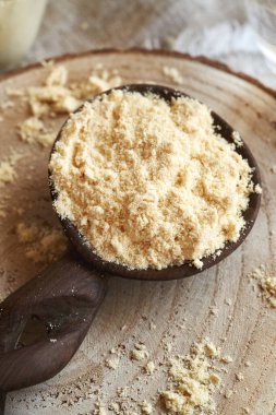 Masadaki tahta kaşıkta bir yığın beyaz protein tozu.