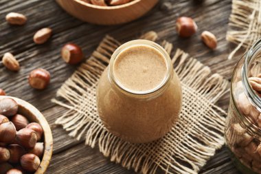 Ahşap bir masada cam kavanozda ev yapımı fındık ezmesi.