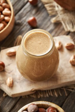 Ahşap bir masada cam kavanozda ev yapımı fındık ezmesi.