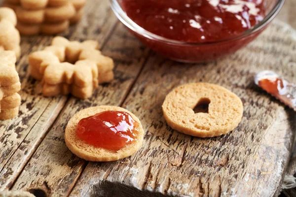 Ev yapımı Linzer Noel kurabiyelerini kırmızı çilekli marmelatla dolduruyorum.