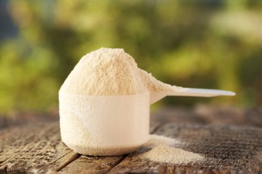 Whey protein powder in a measuring cup on a table outdoors