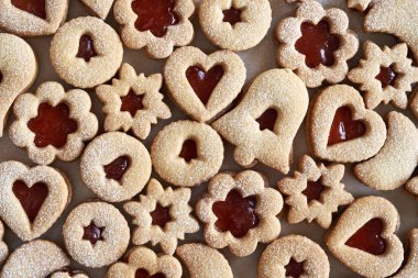 Background made of homemade Linzer Christmas cookies filled with red marmalade and dusted with sugar, top view