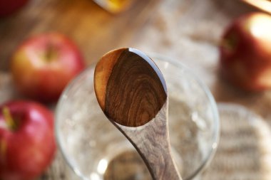 Apple cider vinegar on a wooden spoon with a glass of water, top view