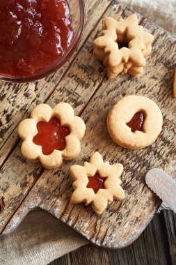 Homemade Linzer Christmas cookies filled with red marmalade on a wooden table, top view