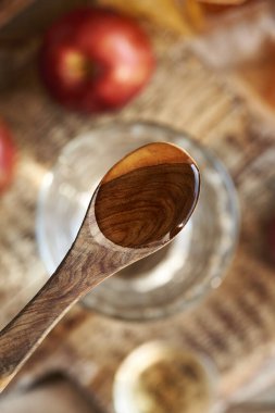 Elma sirkesi ahşap bir kaşıkta, bir bardak suyun üstünde, üst manzara.