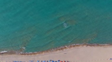Aerial view of turquoise sea waves gently rolling onto sandy beach