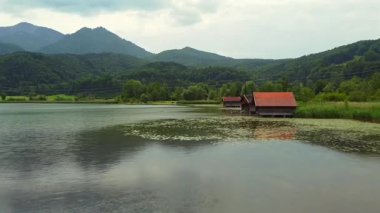 Lake view with wooden boathouses reeds hills and mountains