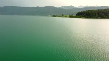 Aerial view of calm alpine lake with forest hills and mountains