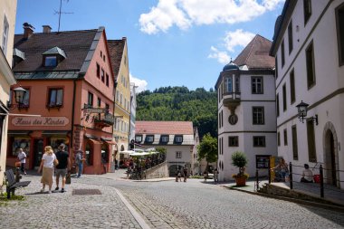 People walking along colorful historic houses and cafes in Fussen Bavaria Germany on June 28 2025 Editorial use only
