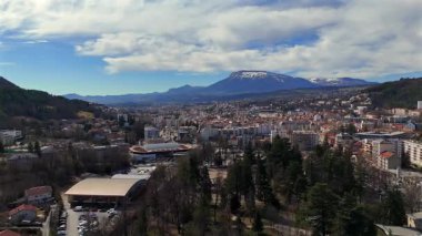 Fransa 'nın güneyindeki Gap şehrinin hava manzarası bulutlu mavi gökyüzünün altında yeşil parklar ve dağ manzaralarını gösteriyor.