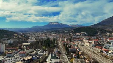 Fransa 'nın güneyindeki Gap şehrinin hava manzarası. Yerleşim binaları, tren istasyonu ve mavi gökyüzünün altındaki bulutlarla çevrili dağlar.